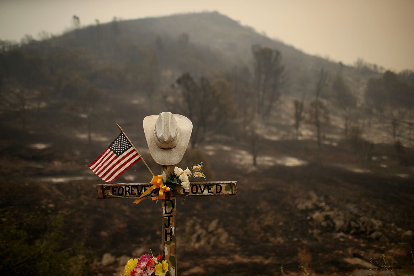 A roadside memorial stands next to an area burned by the Detwiler fire in Mariposa, Calif.
