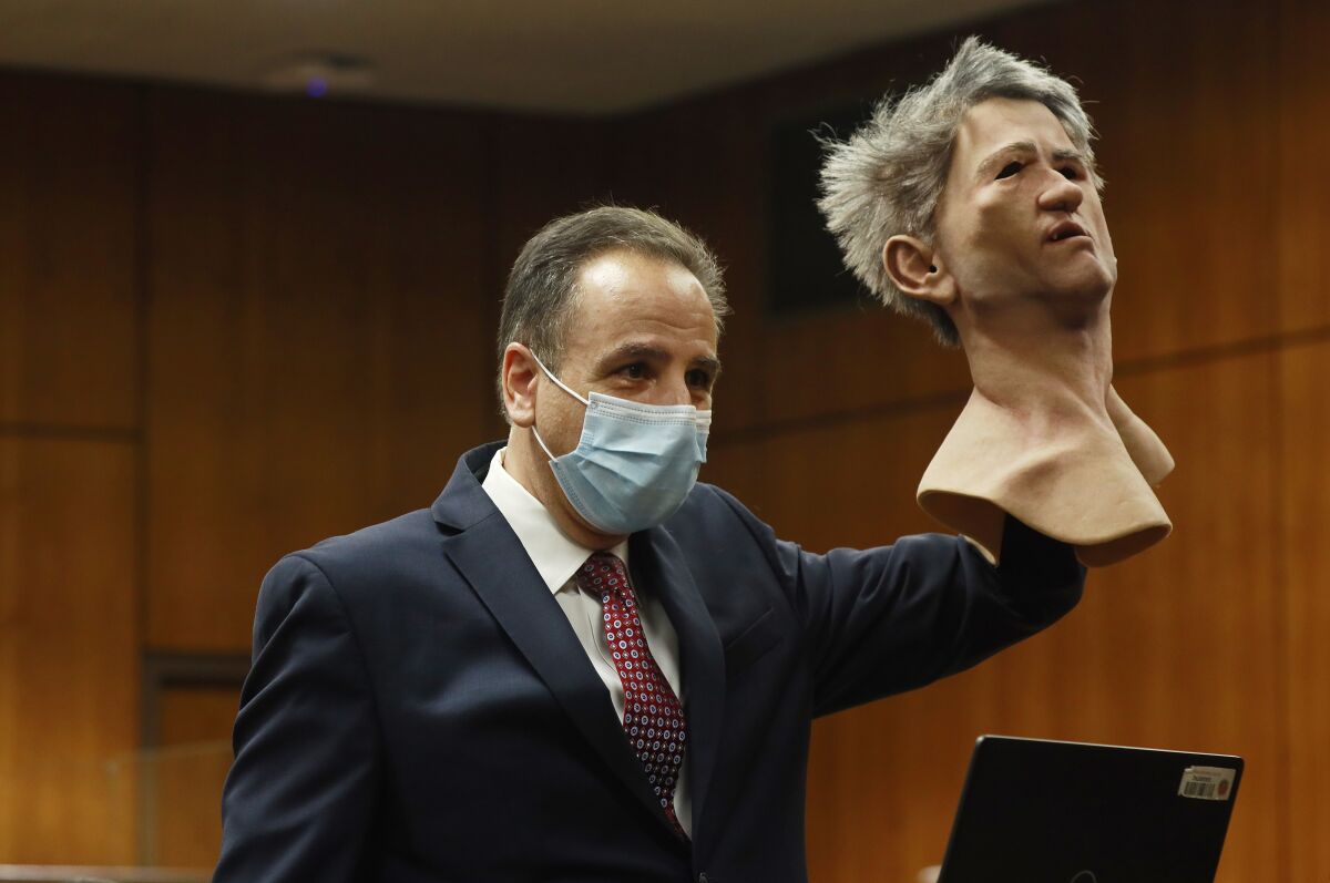 An attorney in court holds up a realistic rubber mask with gray hair