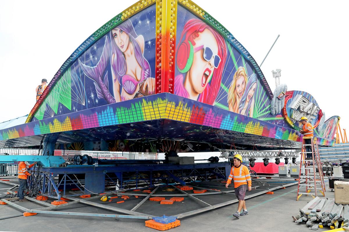 RCS carnival workers set up a Rave Wave ride as preparations for the 2021 O.C. Fair take place on Tuesday in Costa Mesa.