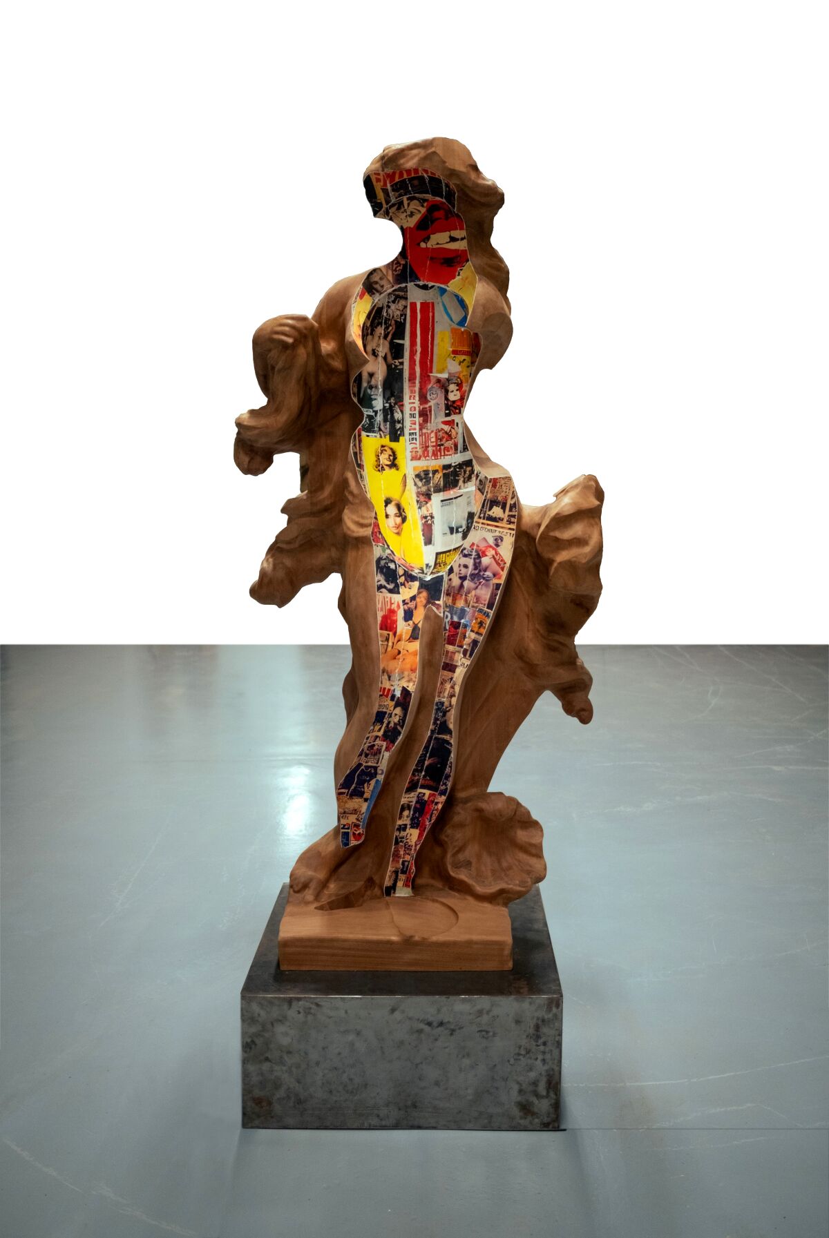 A wood sculpture of a female-looking figure on a pedestal.