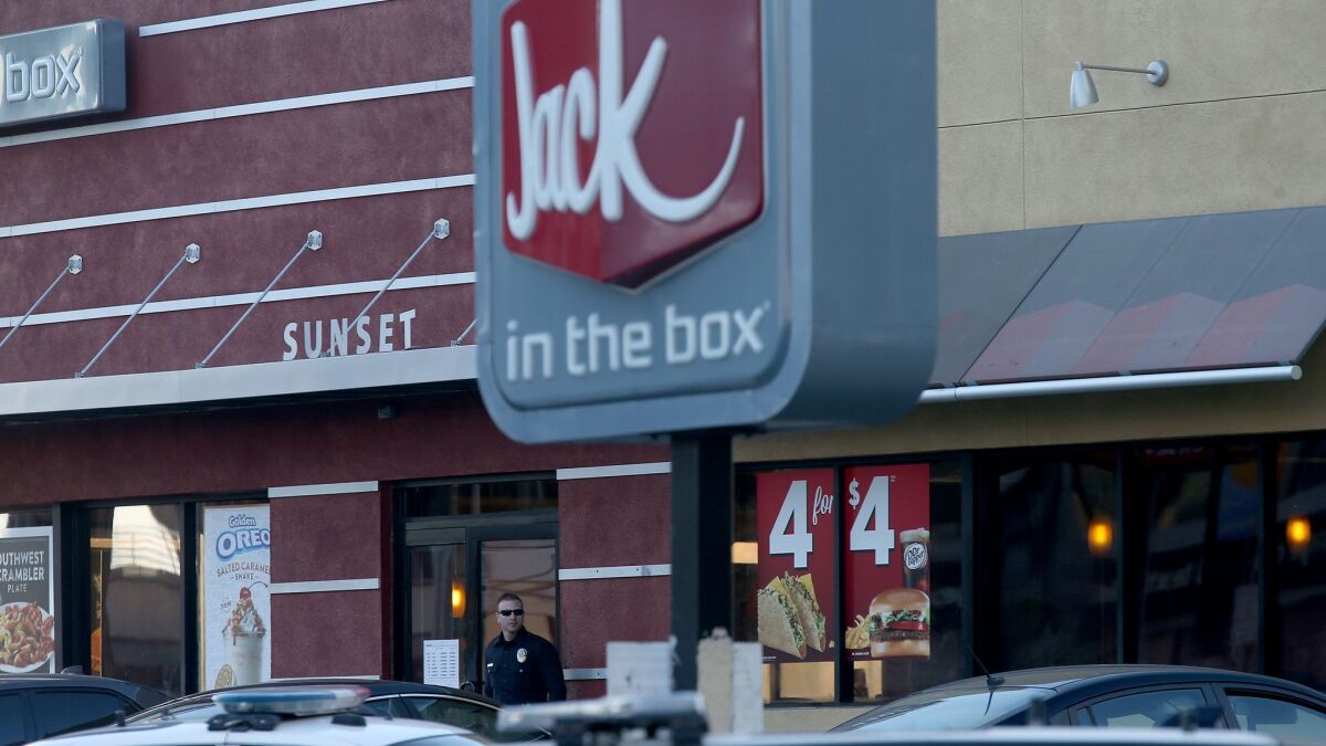 Two men were killed over two days in separate shootings at Jack in the Box restaurants. In this file photo, an LAPD officer stands guard outside a Hollywood restaurant where three people were stabbed and another was fatally shot in 2017.