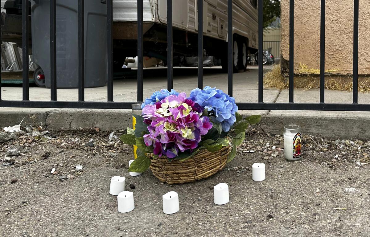Candles on the ground surround a basket of flowers.