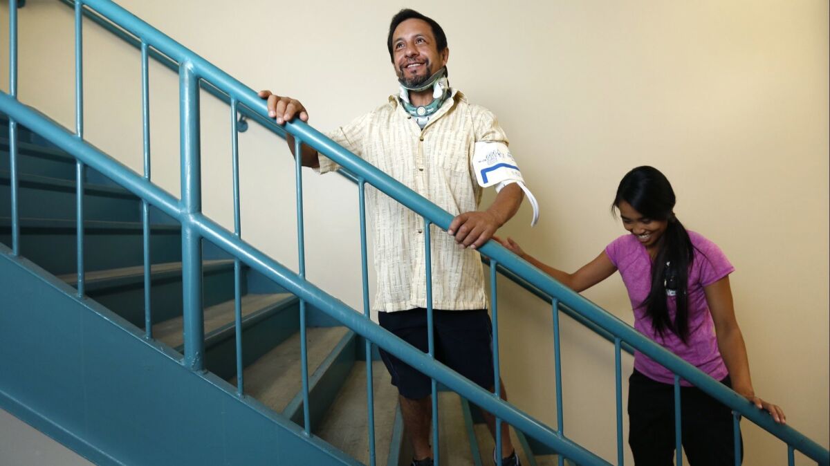 Victor Espinoza walks stairs during a physical therapy session with the help of physical therapist Christina Dinh.