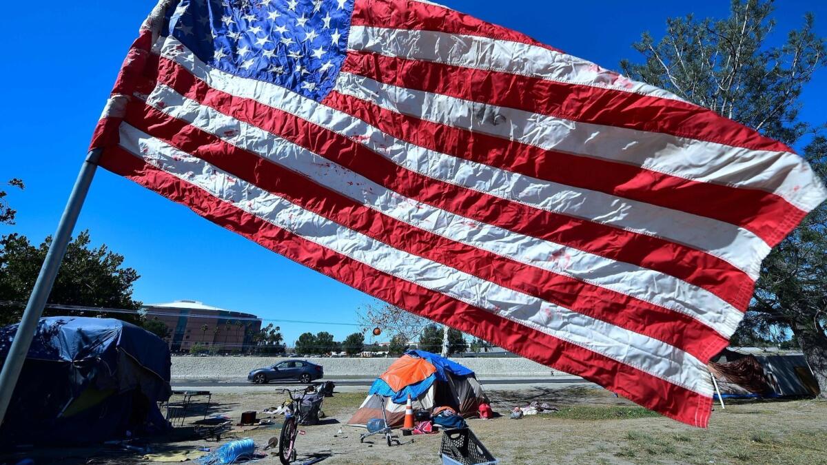 A U.S. flag flies near a tent at homeless people's encampment beside the Santa Ana River in Anaheim on Feb. 20.