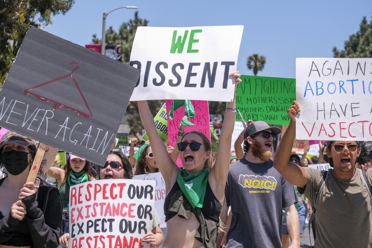 Abortion-rights demonstrators hold signs and march.