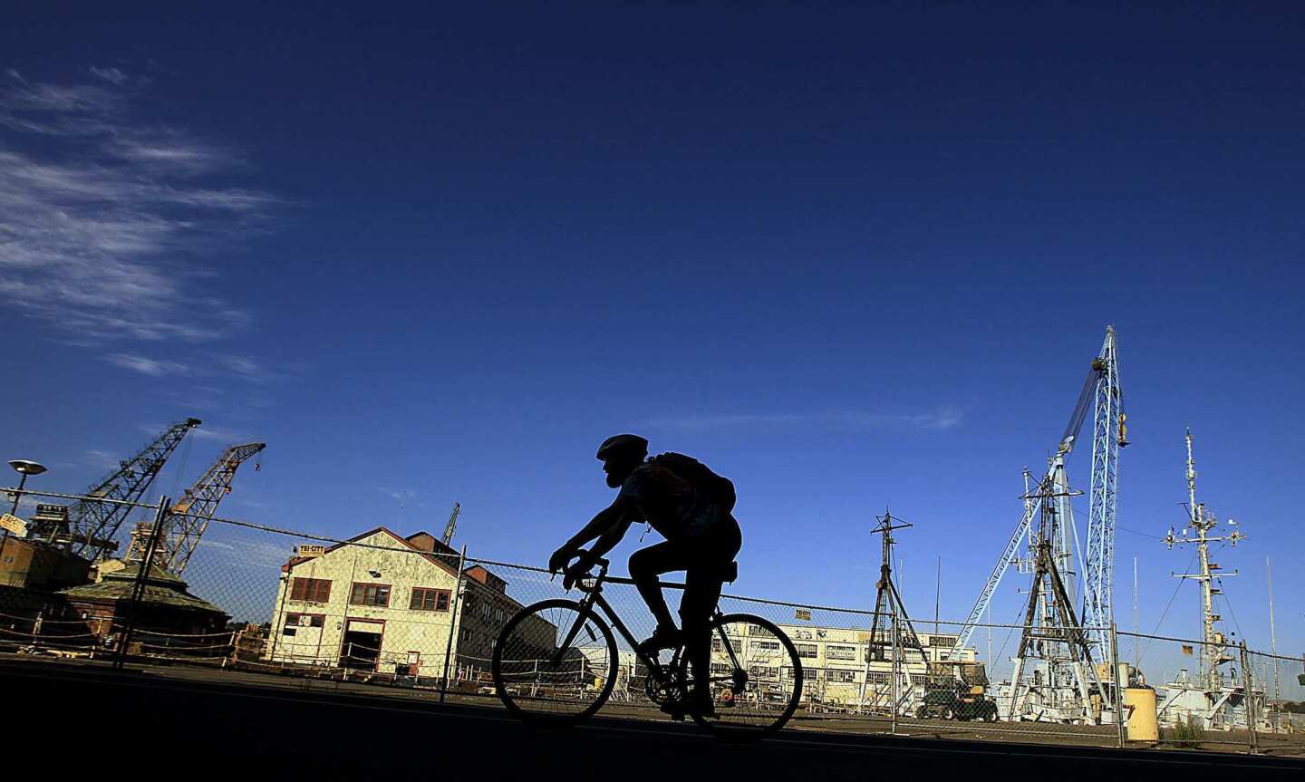 A bicyclist pedals past the shuttered Mare Island Naval Shipyard in the Bay Area community of Vallejo.