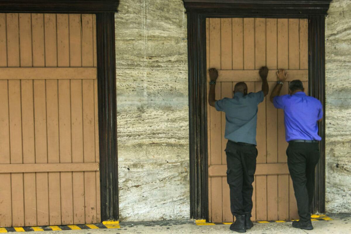 Residentes cierran una farmacia mientras se preparan para la llegada de la Tormenta Tropical Dorian a Bridgetown, Barbados.