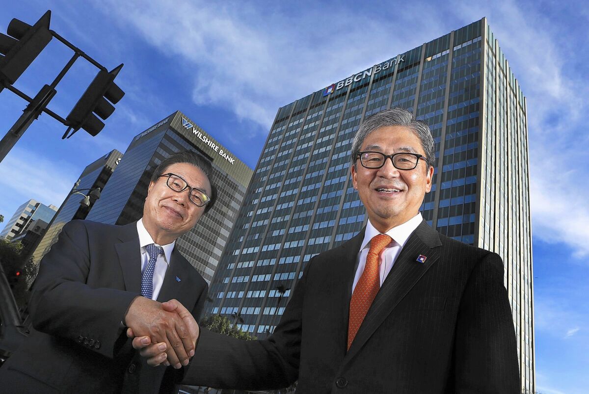 Steven Koh, left, chairman of Wilshire Bancorp, and Kevin Kim, BBCN Bancorp's chairman and CEO, shake hands in December.