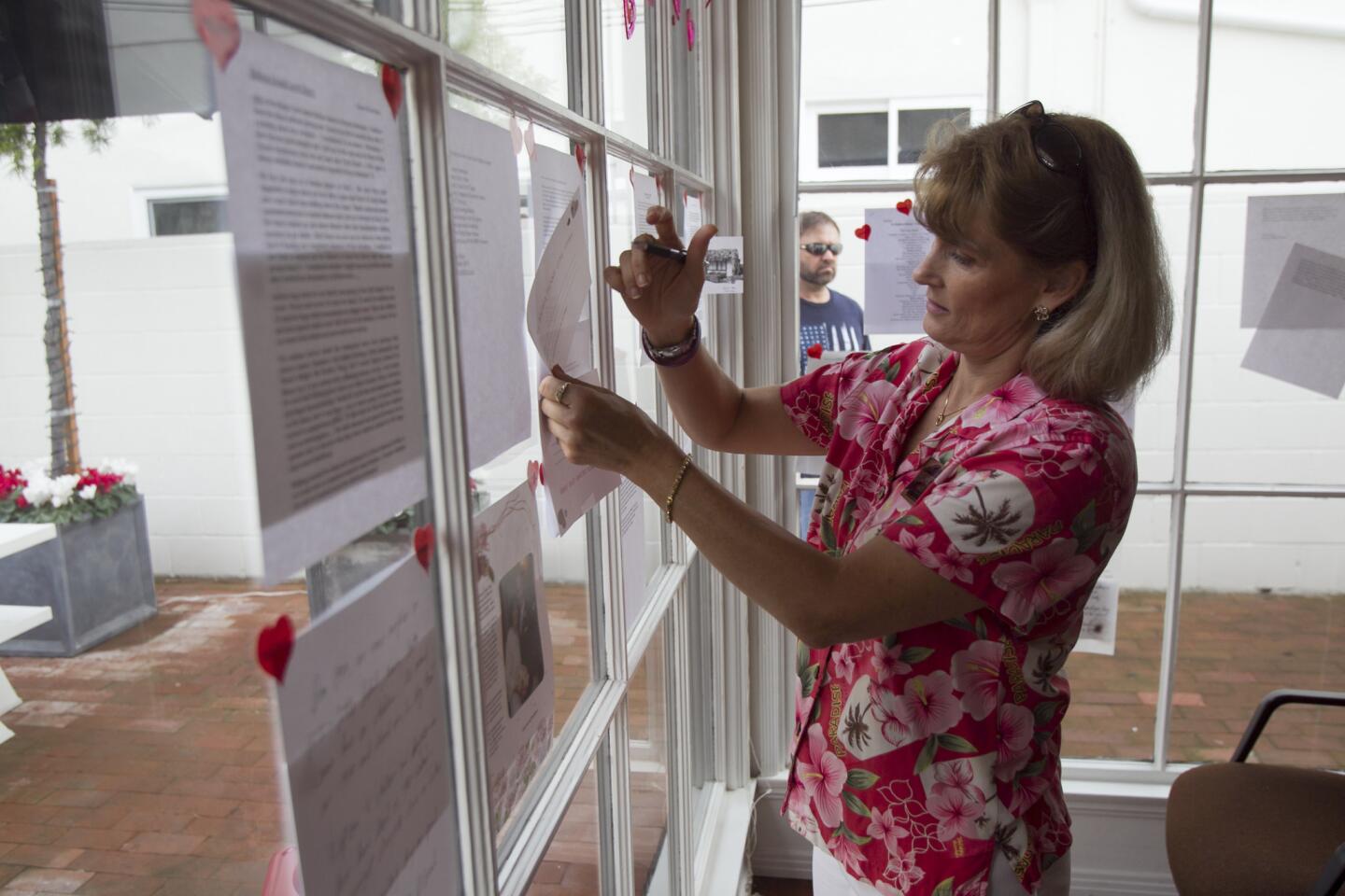 Jackie Smith, a docent at the Balboa Island Museum & Historical Society, hangs a love letter about Balboa Island on the windows at the museum on Saturday, February 15. (Scott Smeltzer, Daily Pilot)