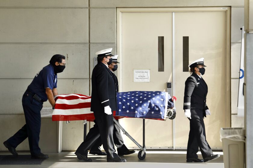 Torrance, California-Jan. 6, 2021-The body of a veteran Los Angeles County firefighter is ushered to the coroner's van for transport from Harbor-UCLA Medical Center in Torrance, CA on Jan. 6, 2021. He lost his life battling a fire in Rancho Palos Verdes on the morning of Jan. 6, 2021. (Carolyn Cole / Los Angeles Times)