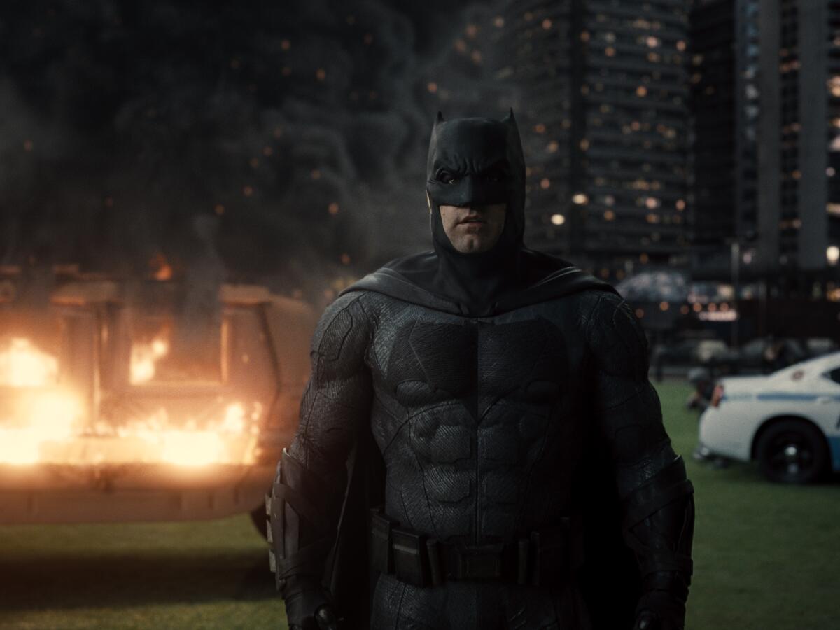 Batman in front of a burning vehicle