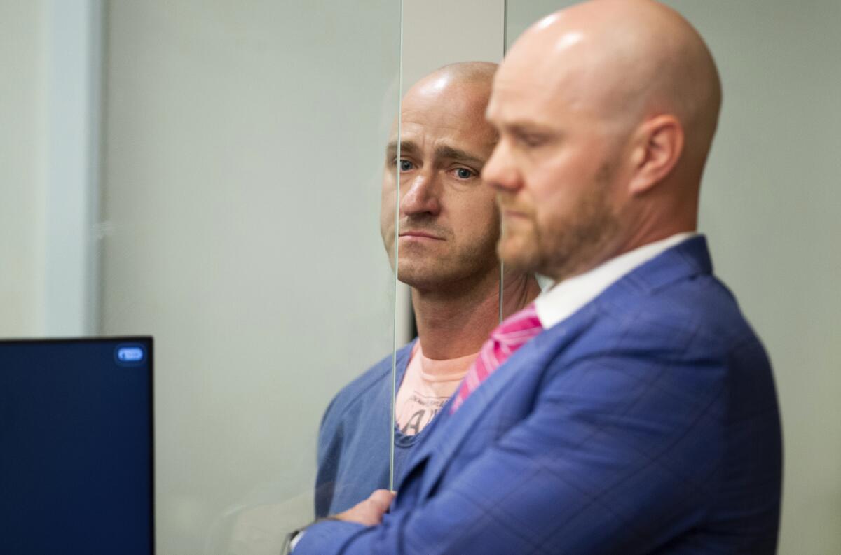 Two men wearing blue stand side-by-side in court