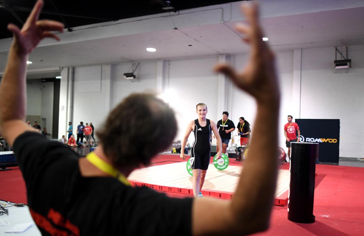 ANAHEIM, CALIFORNIA JUNE 28, 2019-Zavia Burton completes a lift as her coach Shane Miller celebrates in the under 13 year-old category at the USA Weightlifting National Youth Championship at the Anaheim Convention Center Friday. (Wally Skalij/Los Angeles Times)