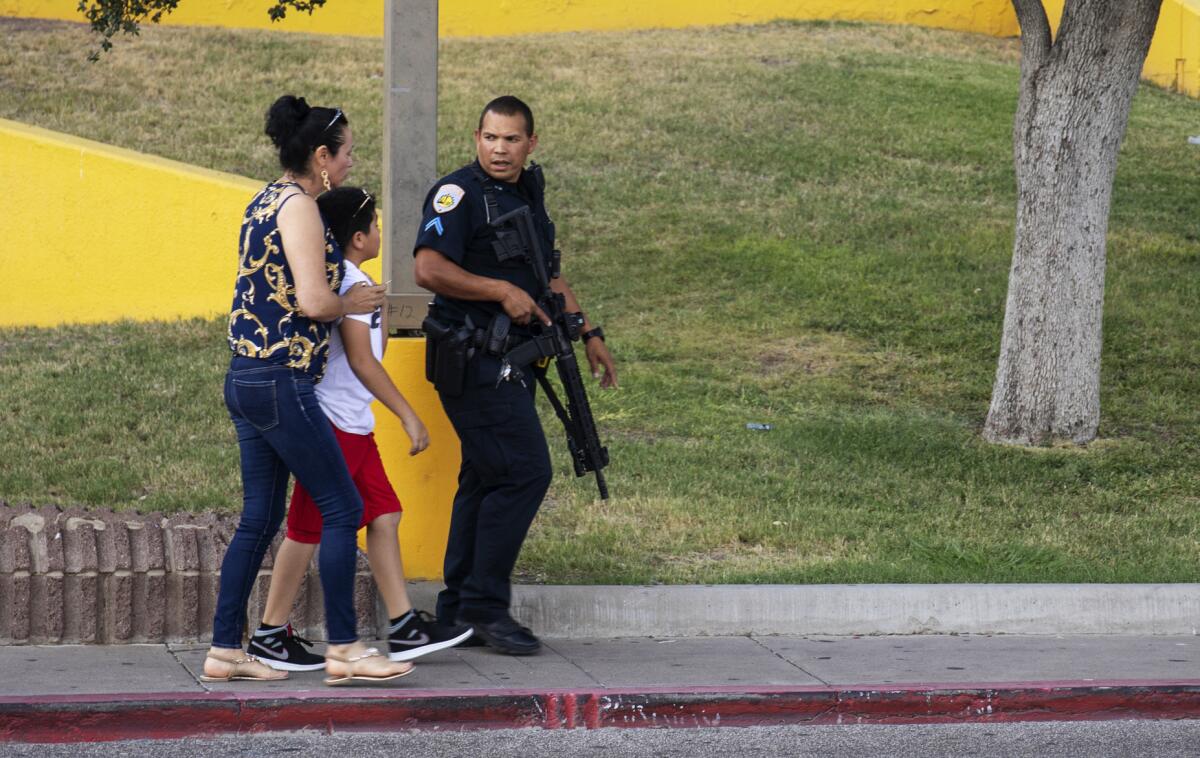 Un oficial de policía escolta a los transeúntes fuera de un área que estaba siendo investigada el sábado después del tiroteo mortal en Odessa, Texas.