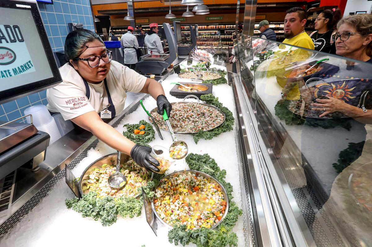 A mariscos bar employee brings out a fresh shrimp cocktail for a guest during opening day.