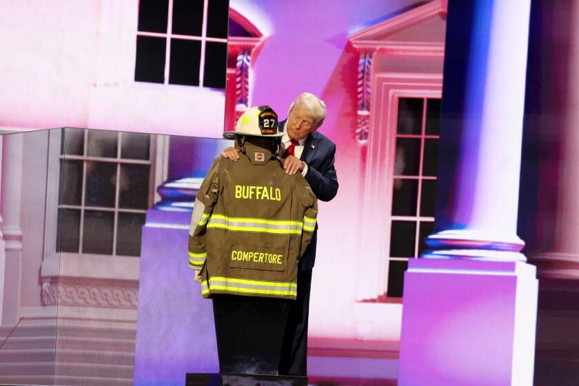 MILWAUKEE, WI JULY 18, 2024 -- Republican presidential candidate former President Donald Trump touches the firefighter gear of Corey Comperatore during the Republican National Convention on Thursday, July 18, 2024. (Jason Almond / Los Angeles Times)