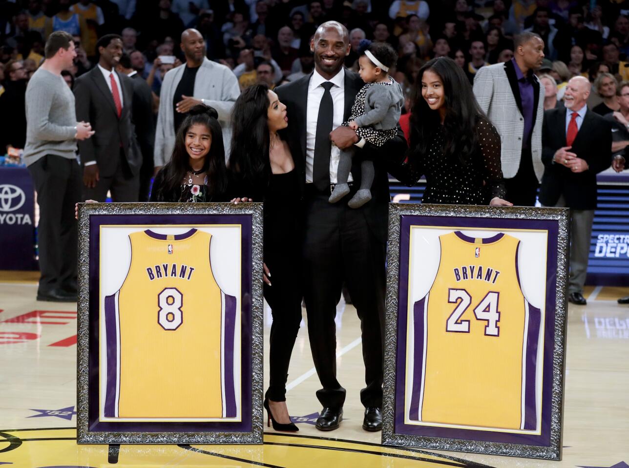 Gianna, Vanessa, Kobe (holding baby Capri) and Natalia Bryant on the court with his two framed retired jerseys.