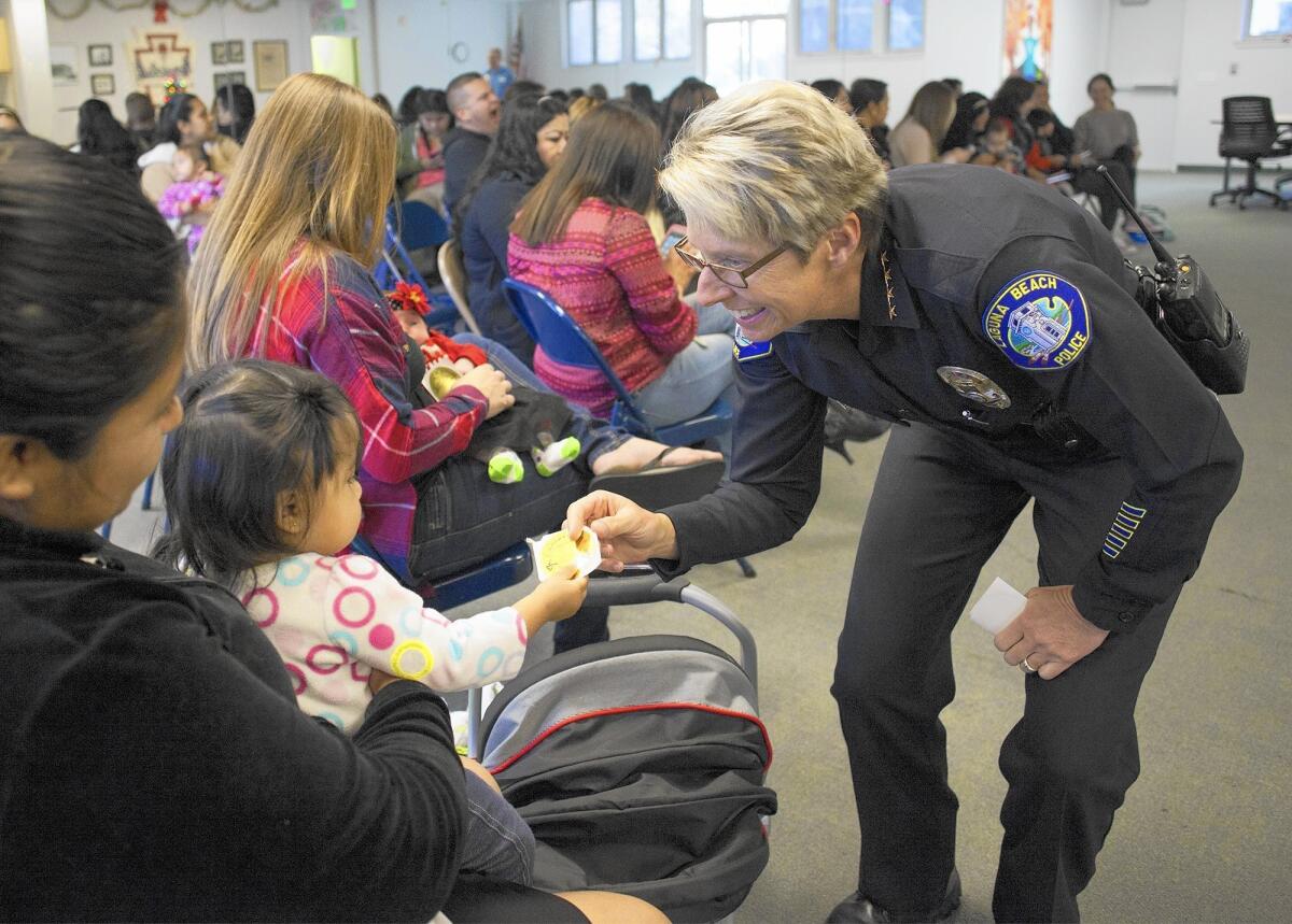 Police Chief Laura Farinella hands a sticker to Jasmine Garcia, 1, at the Boys and Girls Club in Laguna Beach Dec. 18, 2015.