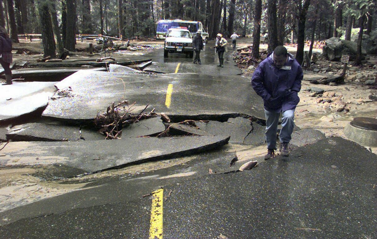 FILE - In this Jan. 5, 1997 photo, Bill Stamps of Fresno, Calif., steps out of a washed-out section of roadway near Happy Isles Nature Center in Yosemite National Park, Calif. Yellowstone National Park, the home to soaring geysers and some of the country's most prolific wildlife is facing its biggest challenge in decades after this week's flooding. Yosemite has flooded several times, none more damaging than 25 years ago when hundreds were stranded as campgrounds were swamped, hotel rooms flooded, bridges and sections of road washed out, power lines downed and a sewage pipe broke. Yosemite was closed to the public for more than two months. (AP Photo/Scott Anger, File)