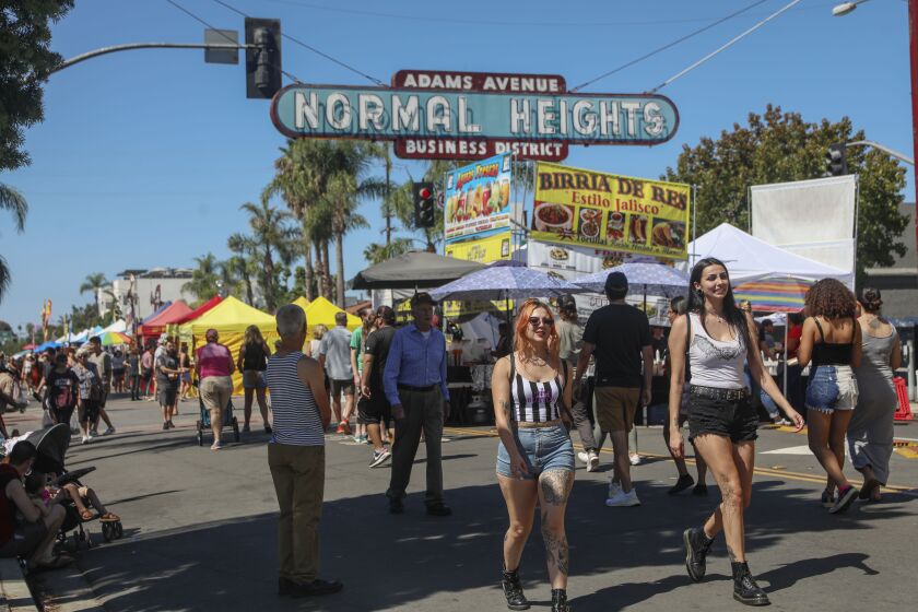Visitors walk along Adams Aveue during the 40th Annual Adams Avenue Street Fair. The street fair is Southern California's largest free two-day music festival and is held each year in September in Normal Heights and features carnival rides, beer gardens, festival foods and 300 arts and crafts booths. (Photo by Sandy huffaker for The San Diego Union-Tribune)