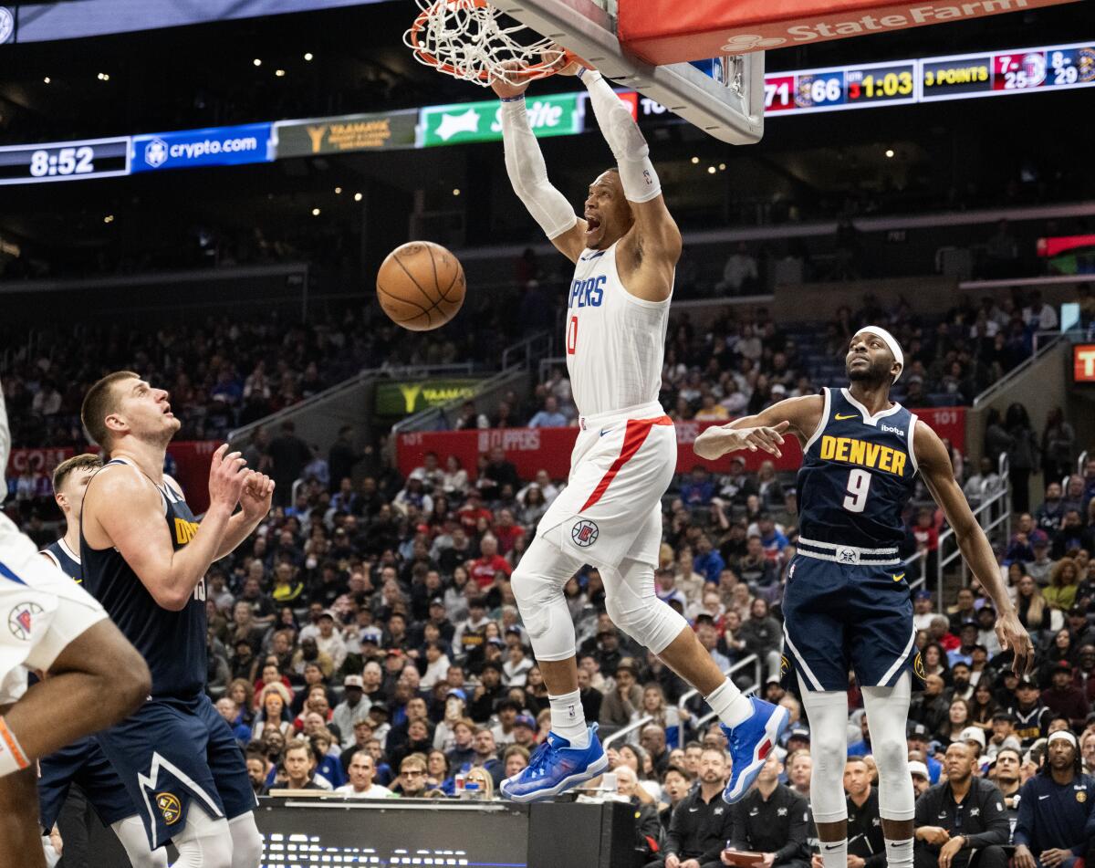 Clippers guard Russell Westbrook dunks over Denver Nuggets center Nikola Jokic and forward Jrue Holiday.