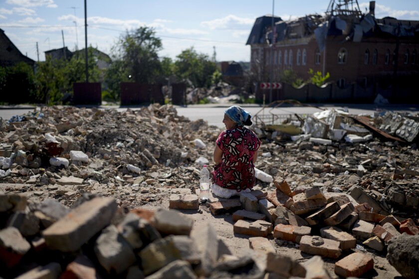 Woman sitting amid building rubble