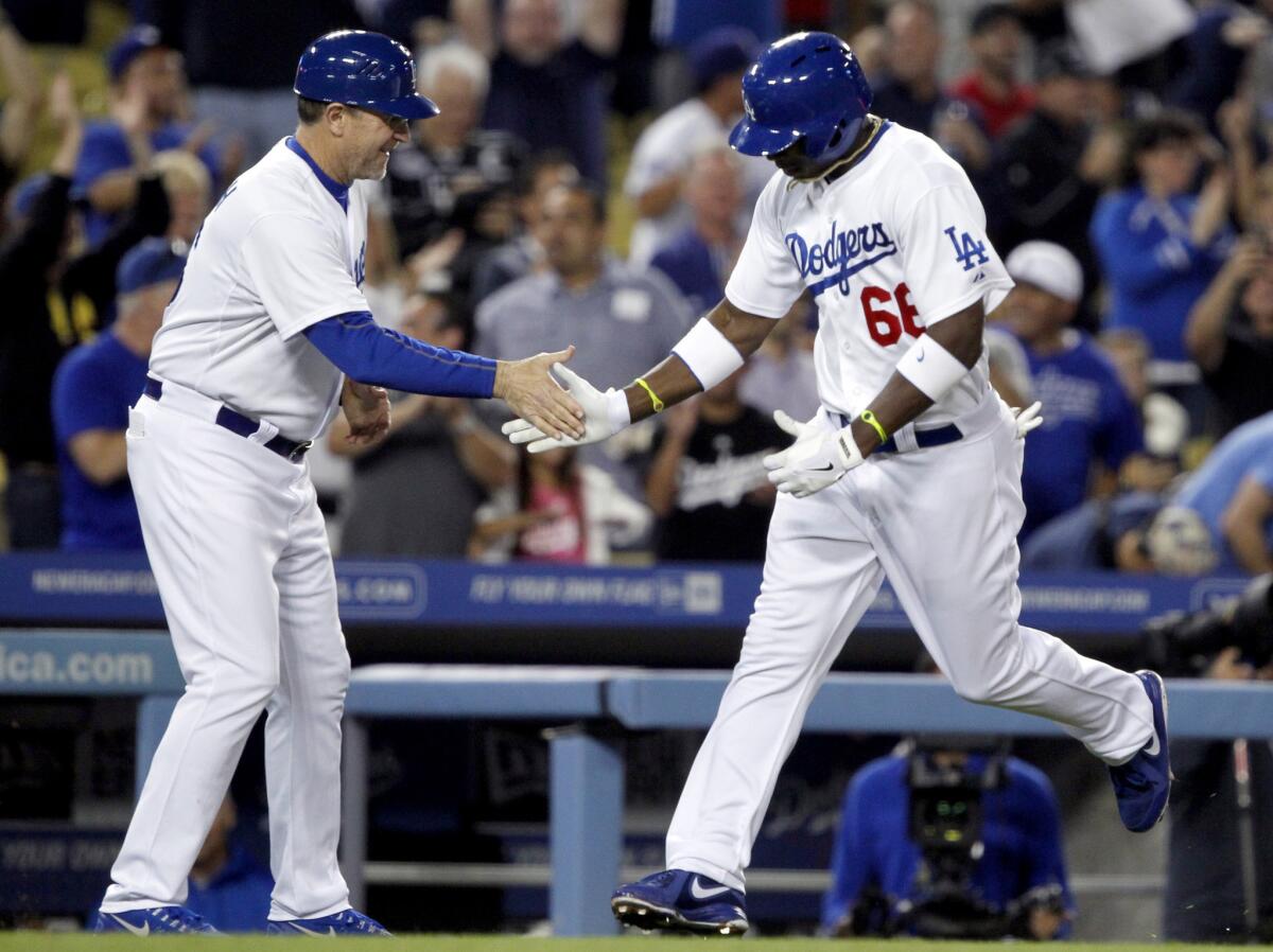 Dodgers' Yasiel Puig, right, is congratulated by third base coach Tim Wallach as he rounds third after hitting a grand slam against the Atlanta Braves.