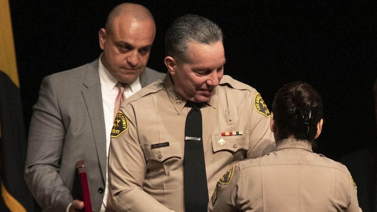 Los Angeles County Sheriff's Deputy Caren Carl Mandoyan, left, looks on as Alex Villanueva prepares to take the oath as Los Angeles County sheriff on Dec. 3, 2018. 