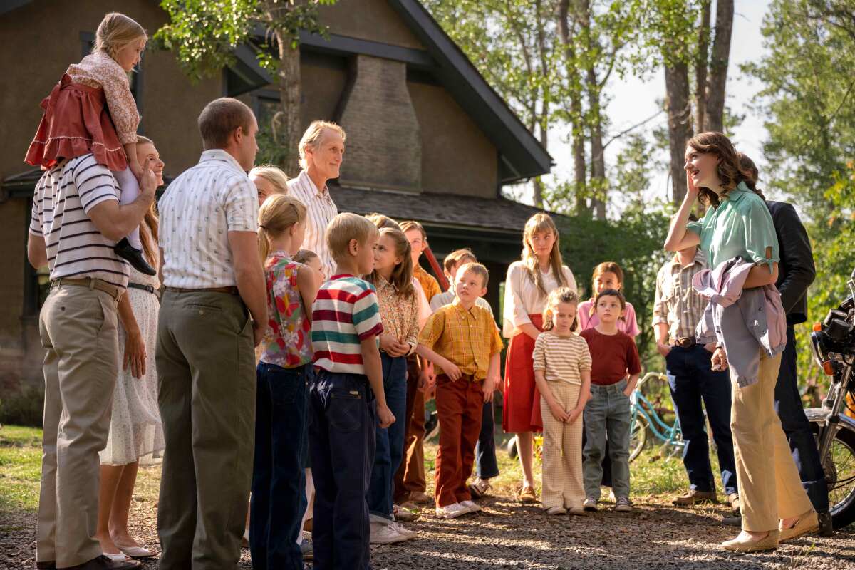 A young woman is greeted by a large, multigenerational family standing in front of their house
