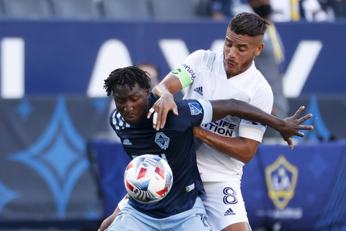 Galaxy midfielder Jonathan dos Santos and Vancouver Whitecaps midfielder Janio Bikel fight for the ball