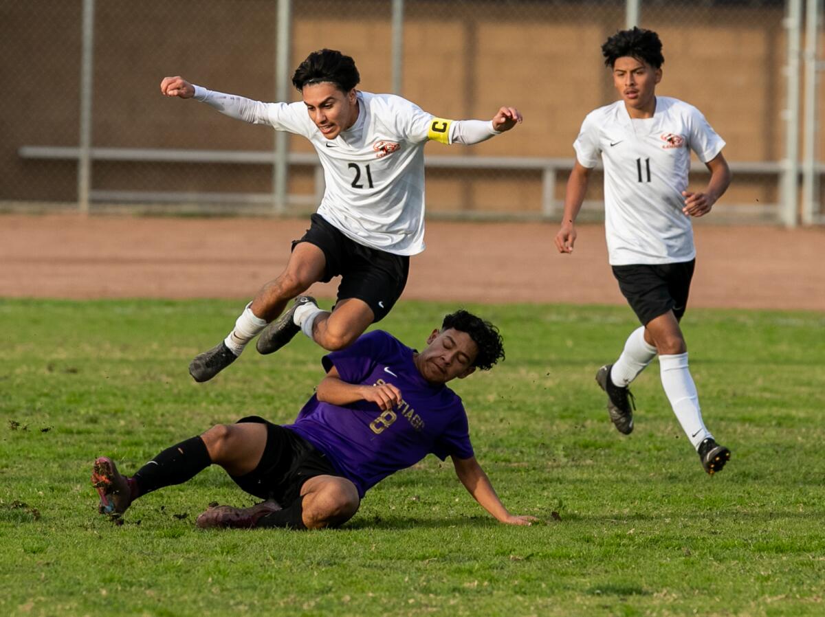 Los Amigos' Randy Arciga leaps over Santiago's Roger Cruz in a Garden Grove League boys' soccer match on Friday.