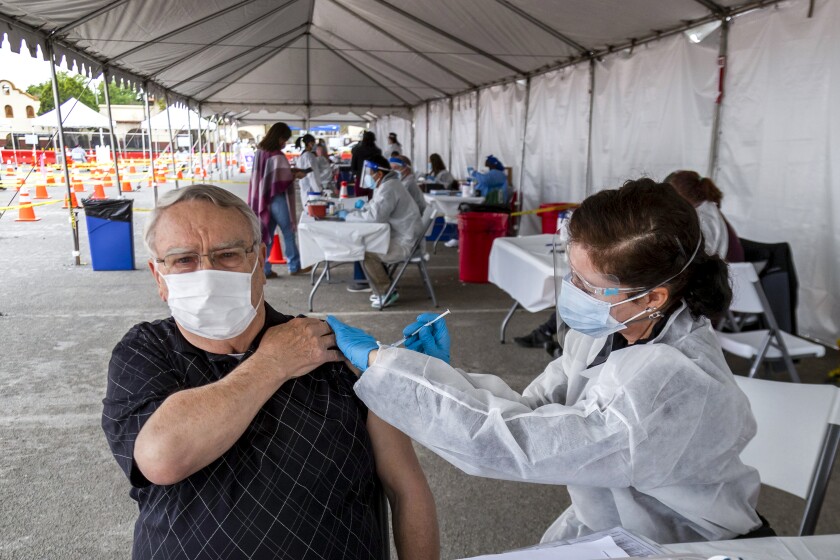 Nurse Susan Eyman administers the Moderna vaccine to Robert Nelson in the parking lot of the Riverside Convention Cente