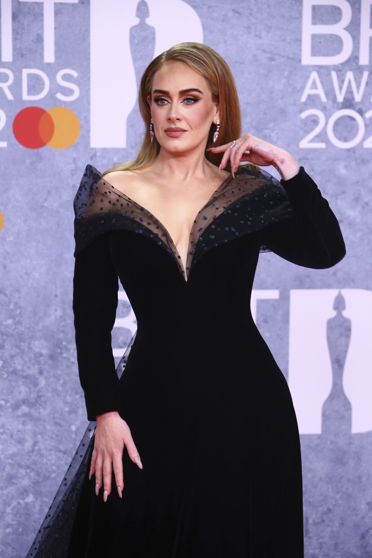 A woman poses in a black gown at a red-carpet event