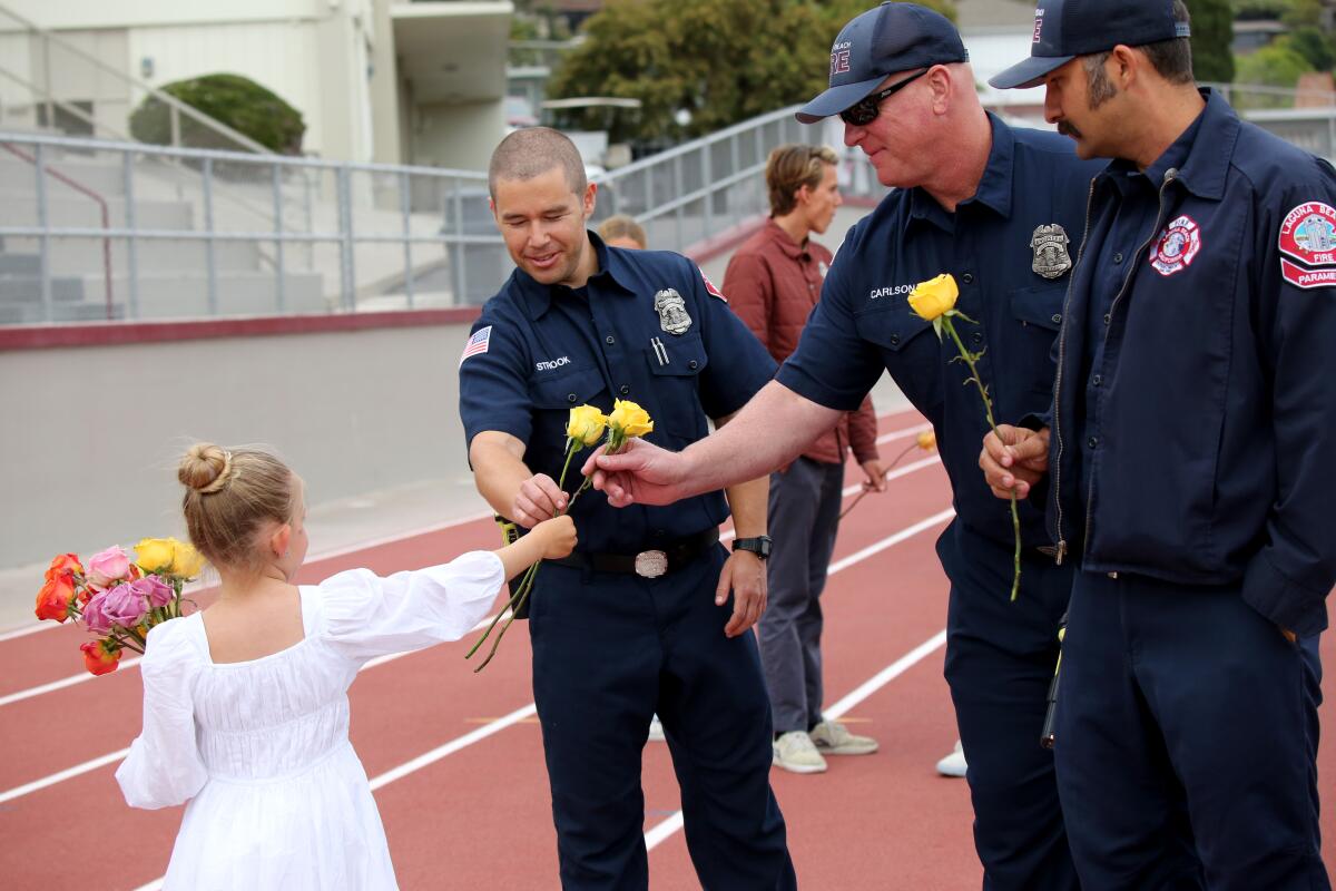 Kindergarten student Isabel Offield hands out flowers to firefighters during a vigil for El Morro principal Chris Duddy.