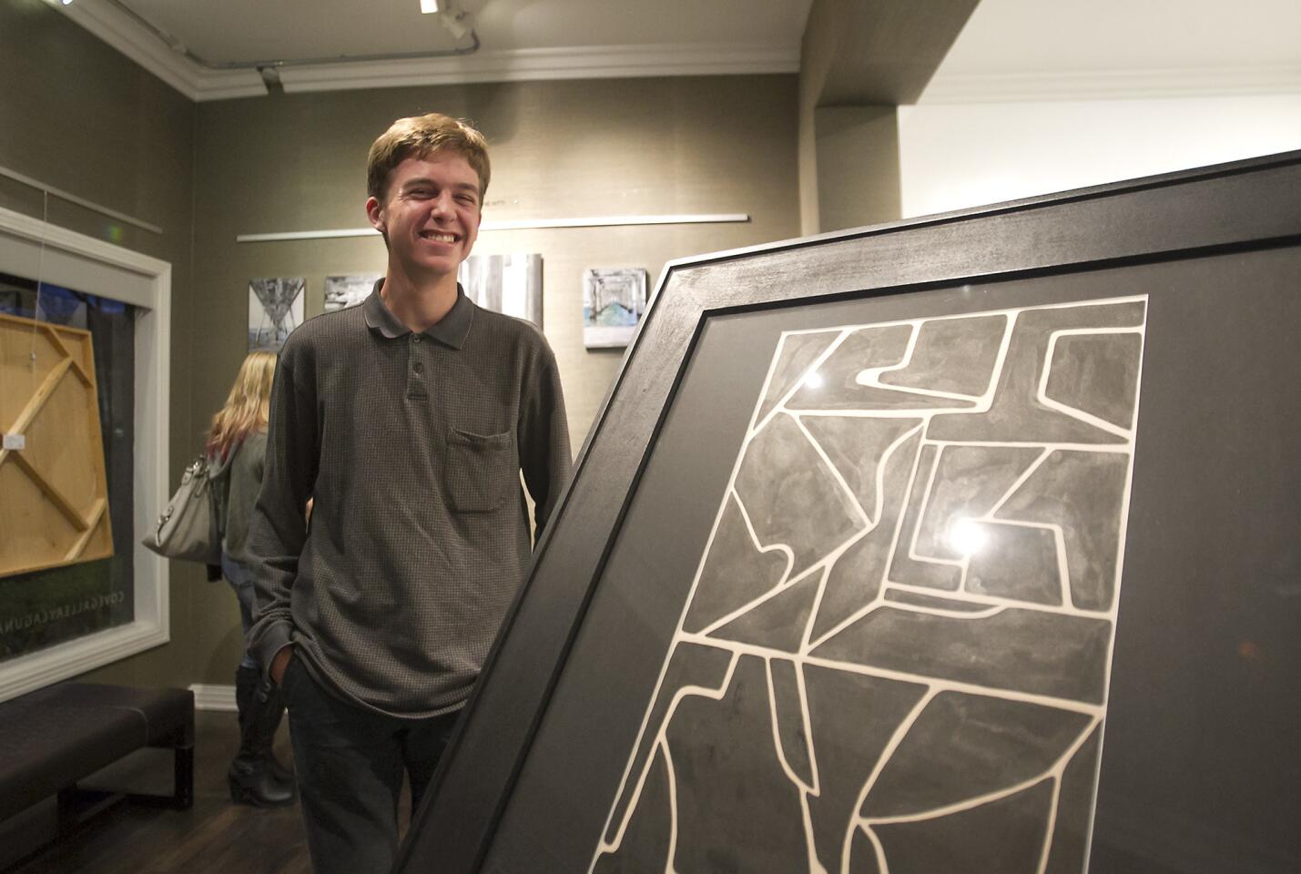 Laguna Beach High student Zander Raymond stands next to his ink on paper piece "Shape Study" at the Cove Gallery on Thursday night's Art Walk