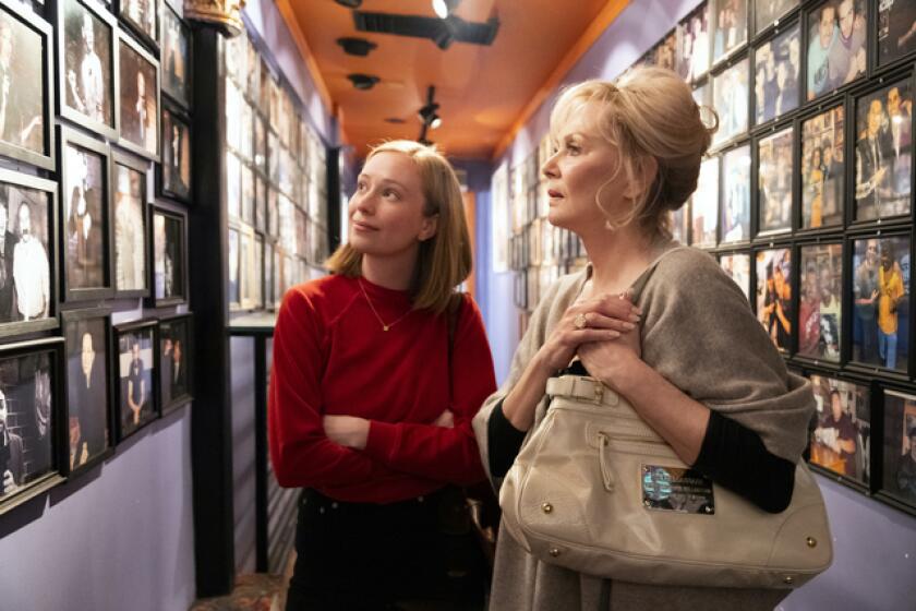 Two women look at photos on the wall of renowned comedy club