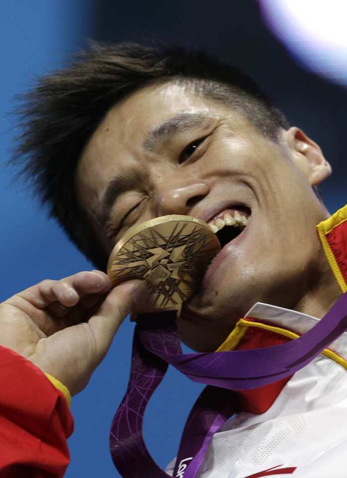 China's Lu Xiaojun bites the gold medal after winning the men's 77kg weightlifting competition.