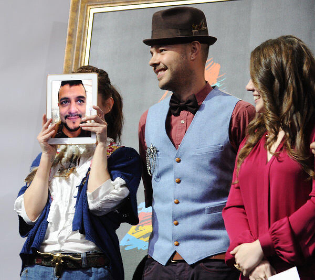 Maria Barracuda, left, of the Mexican pop group Jotdog hides behind a live iPad image of her Jotdog partner Jorge "La Chiquis" Amaro at the 13th annual Latin Grammy Awards nominations press conference in L.A. last September. With her are Jesse, center, and Joy Huerta of the Mexican pop duo Jesse & Joy.