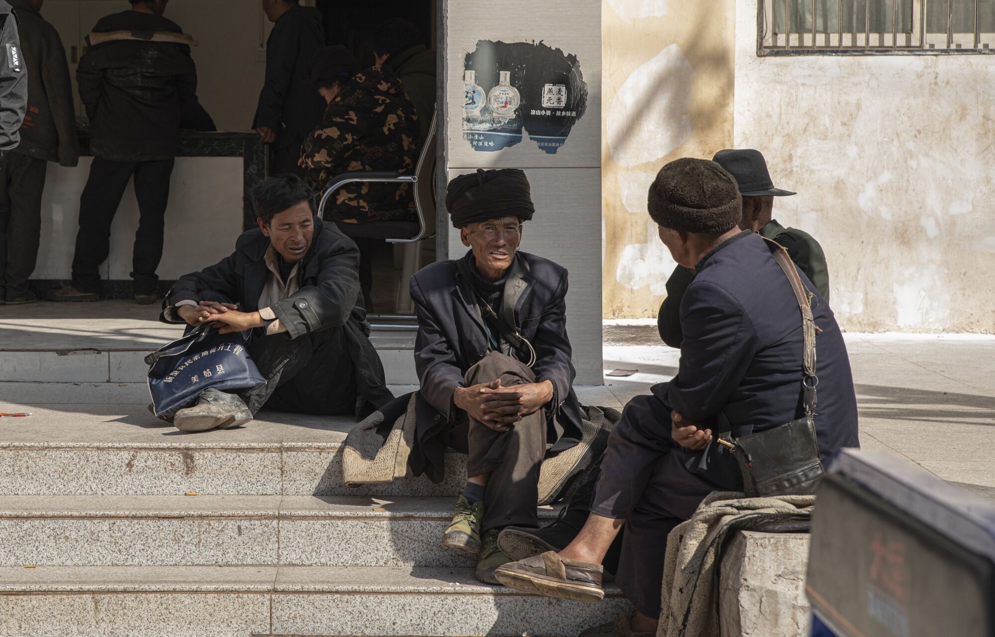 A group of men sit on steps outside a building 