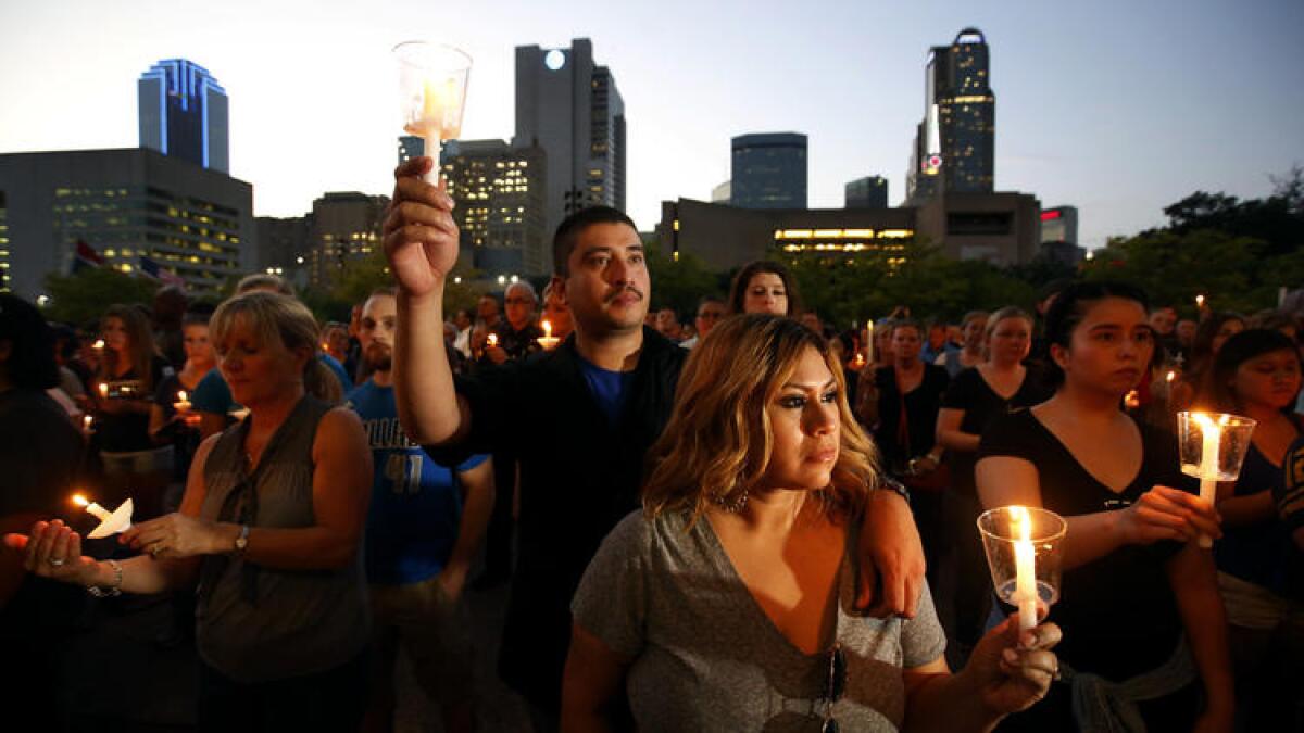 Dallas Police Officer Victor Guzman, who was on the sniper shooting scene, holds a candle with his wife, Ciprina, as family and friends of fallen police officers take part in a candlelight vigil at City Hall in Dallas.