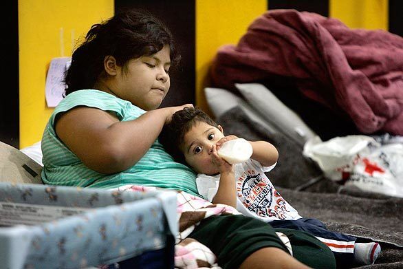 Linda Escobedo, 11, combs her 9-month old nephew Daniel's hair at the San Fernando High Red Cross Evacuation Center. The Escobedo family lived in a trailer at the Sky Terrace Lodge mobile home park that was destroyed in the Marek fire.