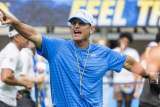 Coach Jim Harbaugh signals his Chargers from the sideline.