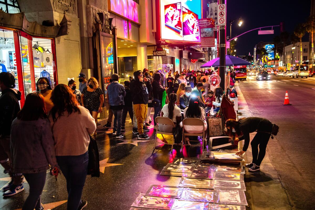 People walk Hollywood Boulevard past shops and street vendors a year into the COVID-19 pandemic.