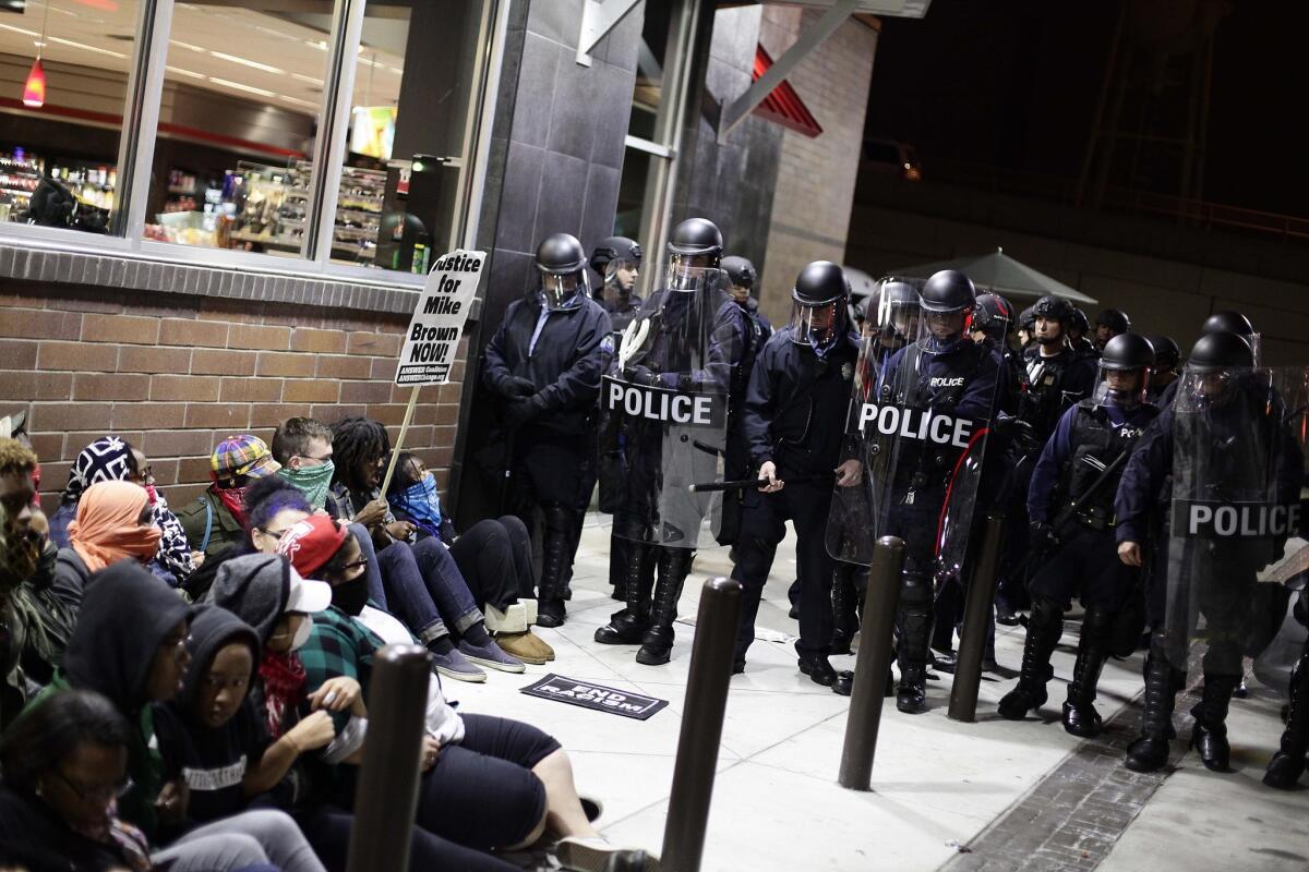 St. Louis police in riot gear face off outside the QuikTrip with demonstrators protesting the shooting deaths of Michael Brown and Vonderrit Myers Jr., both 18.