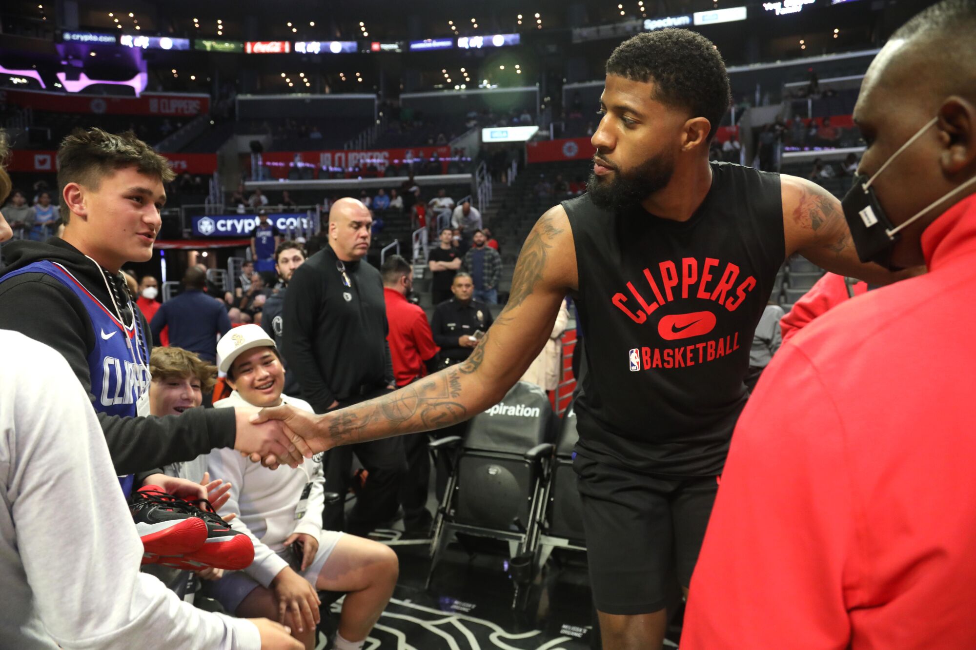Clippers forward Paul George greets a fan courtside before a game.