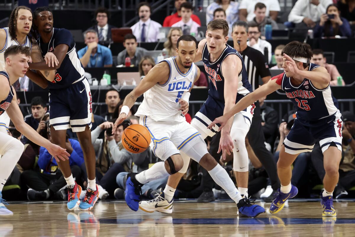 UCLA guard Amari Bailey controls the ball under pressure from Arizona forward Azuolas Tubelis and guard Kerr Kriisa.