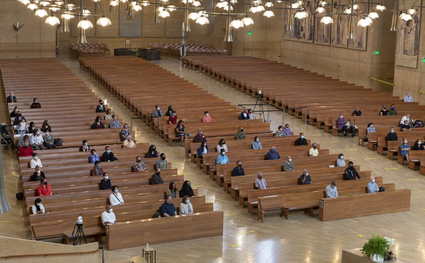 FILE - In this Sunday, June 7, 2020, file photo, a hundred faithful sit while minding social distancing, listening to Los Angeles Archbishop Jose H. Gomez celebrate Mass at Cathedral of Our Lady of the Angels, the first Mass held in English at the site since the re-opening of churches, in downtown Los Angeles. The Supreme Court is telling California it can’t enforce a ban on indoor church services because of the coronavirus pandemic. The high court issued orders late Friday, Feb. 5, 2021, in two cases where churches had sued over coronavirus-related restrictions in the state(AP Photo/Damian Dovarganes, File)