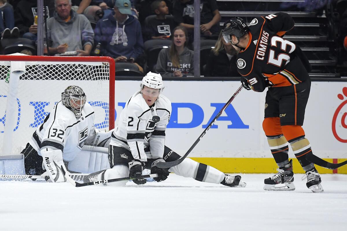 Kings defenseman Paul LaDue, center, stops a shot by Anaheim Ducks left wing Max Comtois in front of goaltender Jonathan Quick.