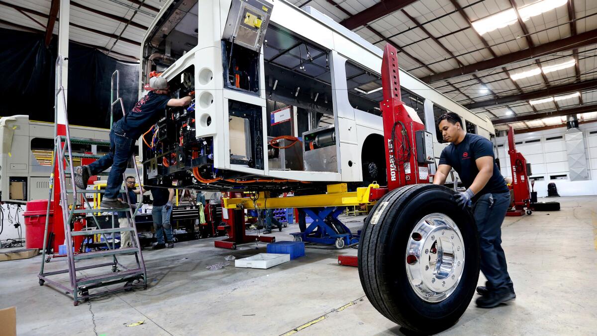 Kevin Mercado rolls a tire into position at an electric bus plant in Lancaster in September. Manufacturing jobs have tanked in the state over the last year.