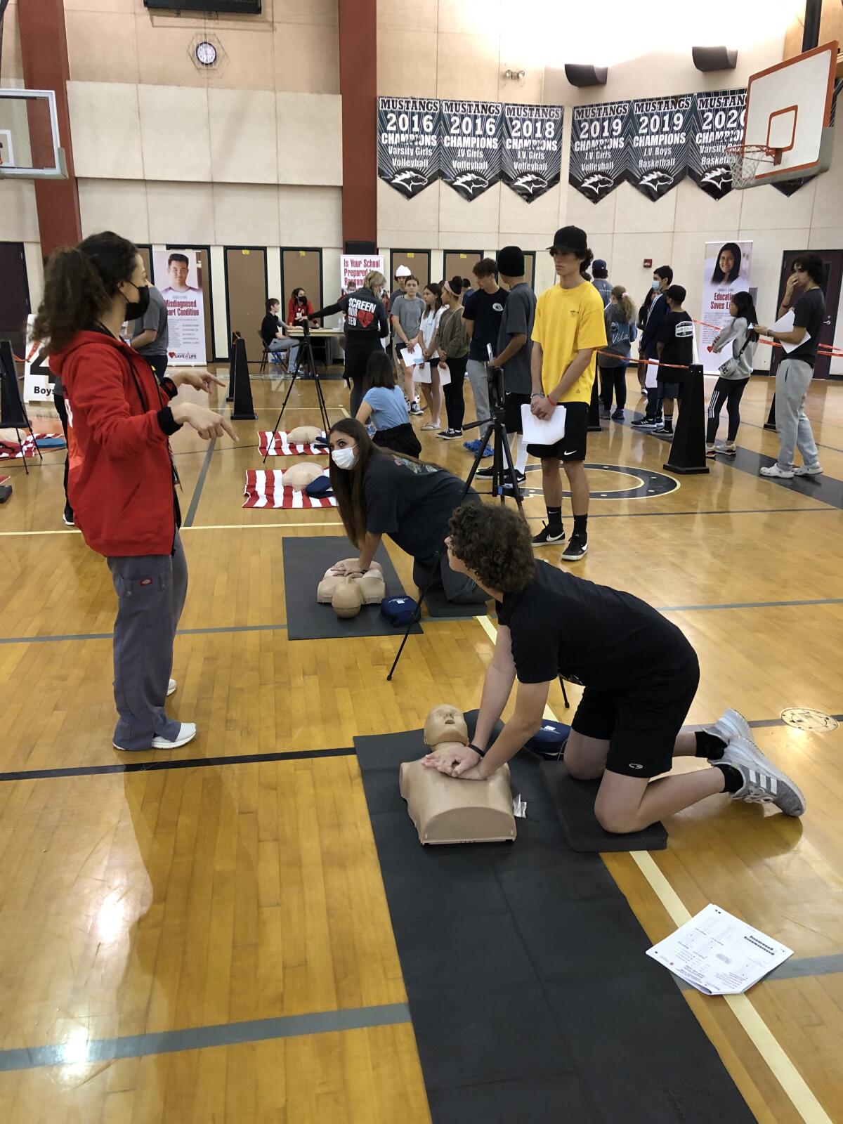 Students practice CPR in an Oceanside middle school gym.
